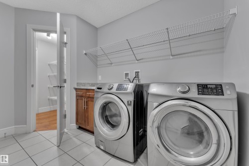 Laundry area featuring a side-by-side washer and dryer, tile flooring, and a built-in wire shelving system - 3363 13 Avenue, Edmonton, AB - Indoor Photo Showing Laundry Room