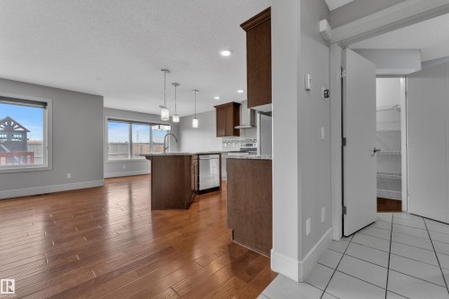 Open-concept living space featuring wood-finish flooring, a kitchen island with pendant lighting, stainless steel appliances, and ample natural light from multiple windows - 3363 13 Avenue, Edmonton, AB - Indoor Photo Showing Kitchen