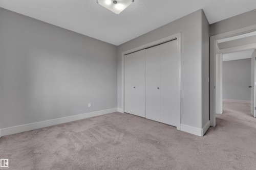 Plush carpet flooring complements neutral gray wall tones - 3363 13 Avenue, Edmonton, AB - Indoor Photo Showing Other Room