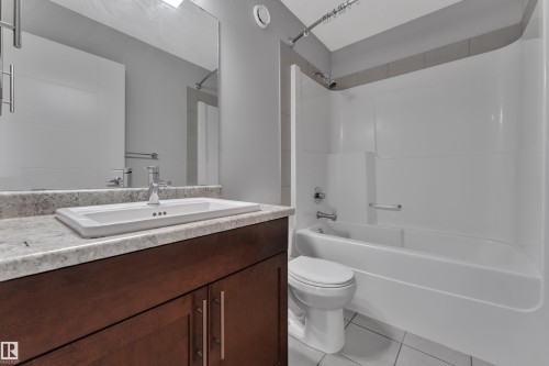 Bathroom featuring a dark wood-finish vanity with a light speckled countertop, an integrated rectangular sink, and a chrome faucet - 3363 13 Avenue, Edmonton, AB - Indoor Photo Showing Bathroom