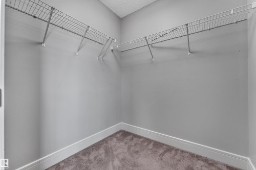 Walk-in closet featuring wire shelving, gray painted walls, a textured ceiling, and gray carpet flooring - 3363 13 Avenue, Edmonton, AB - Indoor With Storage