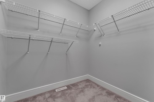 Walk-in closet featuring wire shelving, gray wall paint, white baseboards, and brown carpeting - 3363 13 Avenue, Edmonton, AB - Indoor With Storage