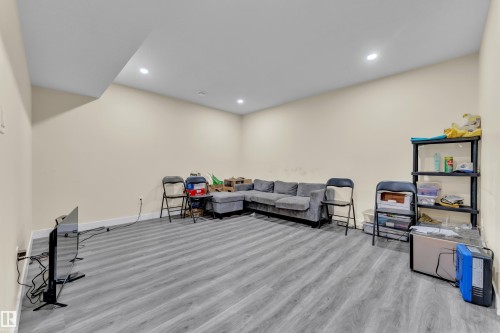 Spacious room featuring light-toned walls, wood-finish flooring, and recessed ceiling lighting - 3363 13 Avenue, Edmonton, AB - Indoor