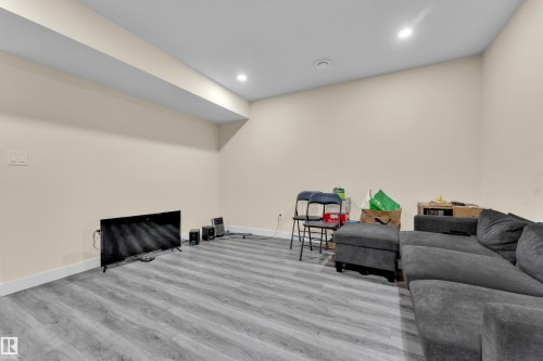 Spacious room featuring light neutral wall paint, recessed lighting, and wood-finish flooring - 3363 13 Avenue, Edmonton, AB - Indoor