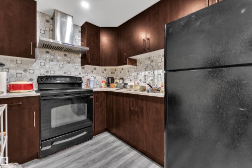 Kitchen featuring wood-finish cabinetry, light countertops, and a patterned tile backsplash - 3363 13 Avenue, Edmonton, AB - Indoor Photo Showing Kitchen