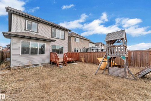 Rear exterior featuring light grey siding, multiple windows, and a raised wood-finish deck - 3363 13 Avenue, Edmonton, AB - Outdoor With Exterior