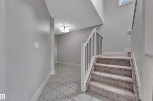 Carpeted staircase with white newel posts and metal spindles - 3363 13 Avenue, Edmonton, AB - Indoor Photo Showing Other Room