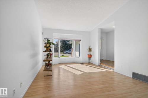 Spacious living area featuring light wood-finish flooring, crisp white walls, and a large bay window - 8403 190 Street, Edmonton, AB - Indoor