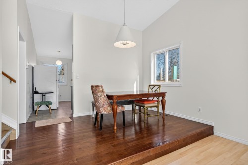 Dining area featuring rich wood-finish flooring on a raised platform, a vaulted ceiling, and a large window - 8403 190 Street, Edmonton, AB - Indoor Photo Showing Dining Room