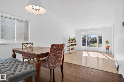 Open-concept living area featuring distinct dark and light wood-finish flooring, white walls, and a large bay window - 8403 190 Street, Edmonton, AB - Indoor