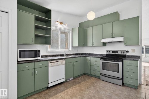 Kitchen featuring green cabinetry, dark laminate countertops, a stainless steel range, and tile flooring - 8403 190 Street, Edmonton, AB - Indoor Photo Showing Kitchen With Double Sink