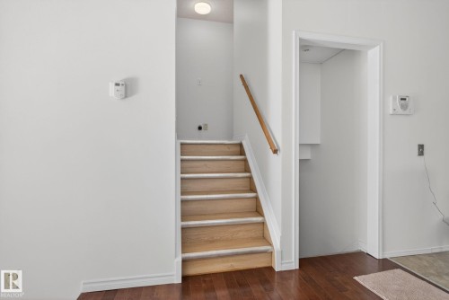 Staircase with light wood treads and a natural wood handrail - 8403 190 Street, Edmonton, AB - Indoor Photo Showing Other Room