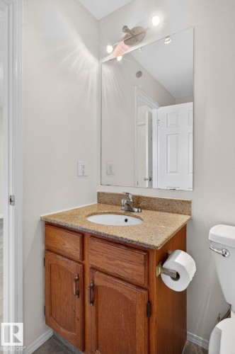 Bathroom vanity featuring a granite countertop, undermount sink, and wood-finish cabinetry with decorative hardware - 8403 190 Street, Edmonton, AB - Indoor Photo Showing Bathroom