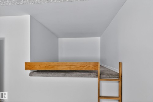 Carpeted loft space featuring a wood safety rail and an integrated wood ladder - 8403 190 Street, Edmonton, AB - Indoor