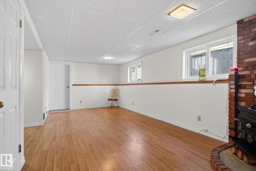 Spacious room featuring wood-finish flooring, white walls, and a drop ceiling - 8403 190 Street, Edmonton, AB - Indoor Photo Showing Other Room