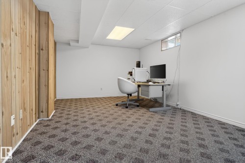 Spacious room featuring patterned carpeting, white walls, and a wood-paneled accent wall - 8403 190 Street, Edmonton, AB - Indoor