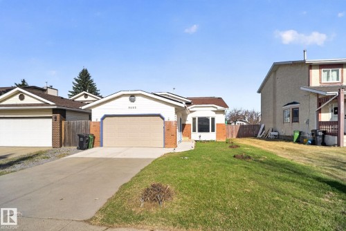 Single-story residence featuring a two-car garage with a tan door, brick facade accents, and a bay window - 8403 190 Street, Edmonton, AB - Outdoor