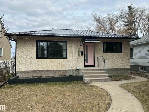 Exterior featuring stucco siding, a black metal roof, and black-trimmed windows - 7550 81 Avenue Nw, Edmonton, AB - Outdoor