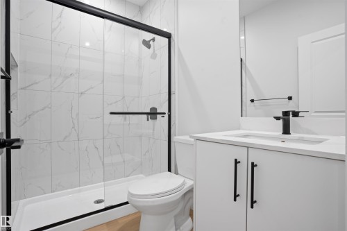 Walk-in shower with clear glass enclosure, matte black hardware, and large format white tile with grey veining - 1849 Crossbill Loop, Edmonton, AB - Indoor Photo Showing Bathroom