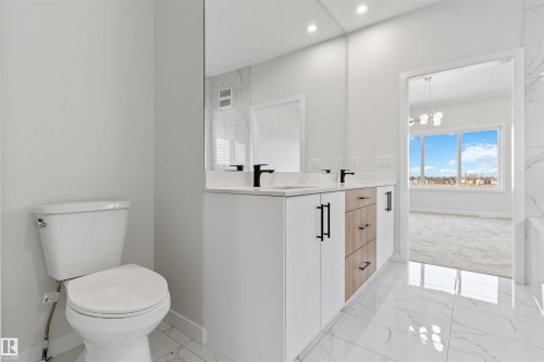 Bathroom featuring a dual vanity with white cabinetry, wood-finish drawers, and matte black hardware - 1849 Crossbill Loop, Edmonton, AB - Indoor Photo Showing Bathroom