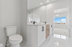 Bathroom featuring a dual vanity with white cabinetry, wood-finish drawers, and matte black hardware - 