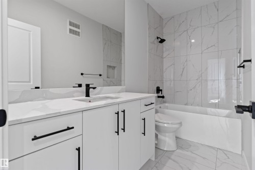 Contemporary bathroom featuring a spacious vanity with an undermount sink, a large mirror, a tiled shower with a built-in niche, and matte black hardware - 1849 Crossbill Loop, Edmonton, AB - Indoor Photo Showing Bathroom