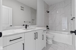 Contemporary bathroom featuring a spacious vanity with an undermount sink, a large mirror, a tiled shower with a built-in niche, and matte black hardware - 