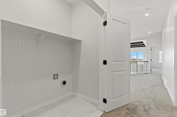Dedicated laundry alcove with a built-in shelf, modern white tile flooring, and essential utility hookups - 