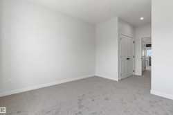 Carpeted room with light gray walls, white trim, and a white paneled door with black hardware - 
