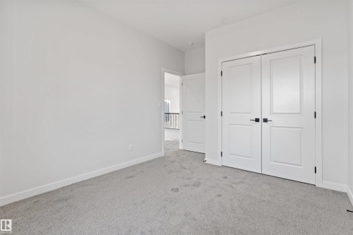 Light gray carpeting complementing white walls, trim, and solid core doors with matte black hardware - 1849 Crossbill Loop, Edmonton, AB - Indoor Photo Showing Other Room