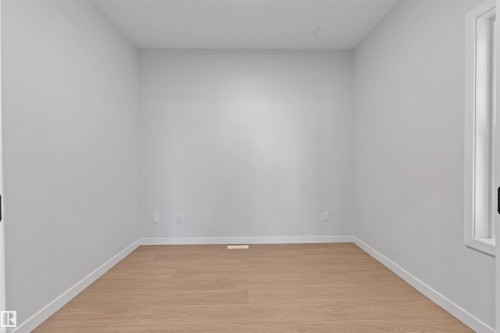 Light wood-finish flooring complements the neutral wall color in this room featuring a window with white trim - 1849 Crossbill Loop, Edmonton, AB - Indoor Photo Showing Other Room