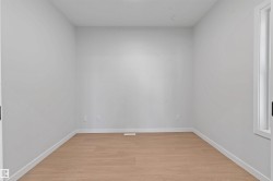 Light wood-finish flooring complements the neutral wall color in this room featuring a window with white trim - 