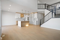 Open-concept living area featuring light wood-finish flooring, recessed lighting, and a modern kitchen - 