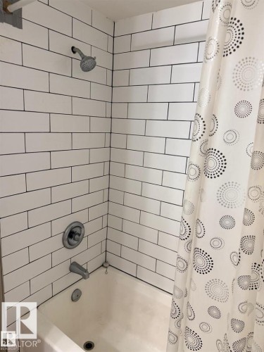 White subway tile shower surround with dark grout, chrome shower head, and chrome tub filler - 106 10725 111 Street, Edmonton, AB - Indoor Photo Showing Bathroom
