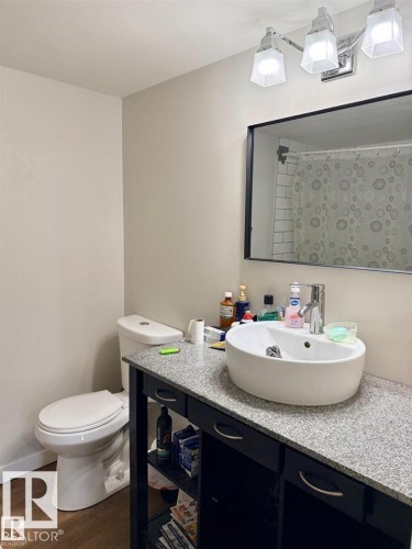 Bathroom featuring a modern vessel sink, granite-finish countertop, and dark wood-finish vanity with open shelving - 106 10725 111 Street, Edmonton, AB - Indoor Photo Showing Bathroom