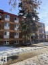 Multi-story brick building featuring a red parapet roofline and numerous windows - 106 10725 111 Street, Edmonton, AB  - Outdoor 