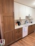 Kitchen featuring wood-finish lower cabinetry, white upper cabinetry, and white countertops - 106 10725 111 Street, Edmonton, AB  - Indoor Photo Showing Kitchen 
