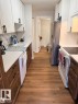 Kitchen featuring wood-finish flooring, white upper cabinetry with matte black hardware, and wood-finish lower cabinetry - 106 10725 111 Street, Edmonton, AB  - Indoor Photo Showing Kitchen 