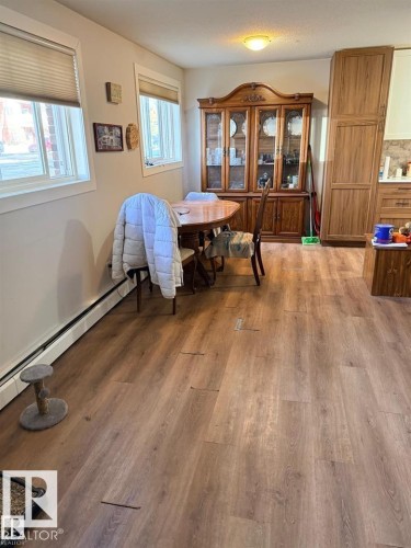 Spacious room featuring wood-finish flooring, two large windows with blinds, and built-in cabinetry providing ample storage - 106 10725 111 Street, Edmonton, AB - Indoor