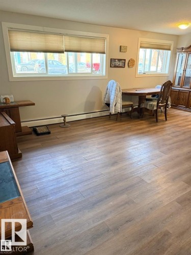 Spacious interior featuring wood-finish flooring, light-toned walls, and multiple windows providing natural light - 106 10725 111 Street, Edmonton, AB - Indoor Photo Showing Other Room