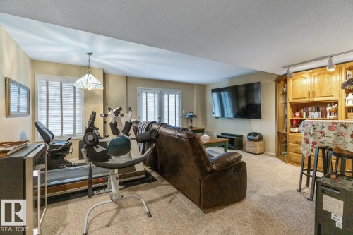 Spacious room featuring neutral carpeting, light beige wall tones, and white trim - 47 1130 Falconer Road, Edmonton, AB - Indoor