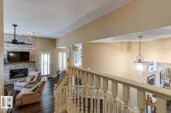 Living area featuring a floor-to-ceiling stacked stone fireplace with a wood mantle, a ceiling fan, and dark wood-finish flooring - 