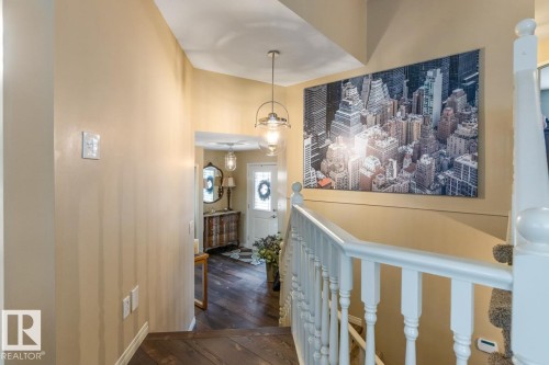 Foyer entrance featuring dark wood-finish flooring and a contemporary pendant light fixture - 47 1130 Falconer Road, Edmonton, AB - Indoor Photo Showing Other Room