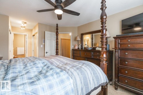 Spacious room featuring neutral painted walls, a dark-bladed ceiling fan with integrated lighting, and carpet flooring - 47 1130 Falconer Road, Edmonton, AB - Indoor Photo Showing Bedroom