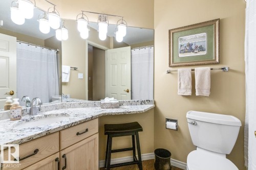 Bathroom vanity with a polished stone countertop, integrated sink, and brushed nickel faucet - 47 1130 Falconer Road, Edmonton, AB - Indoor Photo Showing Bathroom