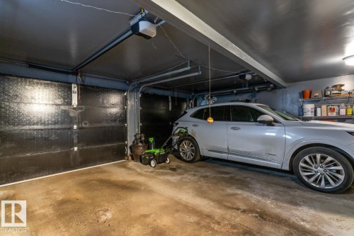 Attached garage featuring an automatic door opener, overhead lighting, and concrete flooring - 47 1130 Falconer Road, Edmonton, AB - Indoor Photo Showing Garage