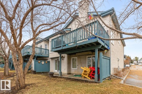 Exterior featuring stucco siding, multiple balconies with teal railings, and a ground-level patio with privacy screening - 47 1130 Falconer Road, Edmonton, AB - Outdoor