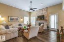 Spacious living area featuring high vaulted ceilings, rich wood-finish flooring, a contemporary ceiling fan, and a floor-to-ceiling stacked stone fireplace with a wood mantle - 47 1130 Falconer Road, Edmonton, AB  - Indoor Photo Showing Living Room With Fireplace 
