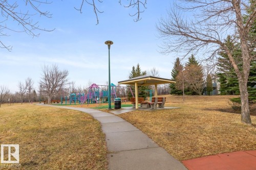 Community park featuring a playground, paved walking path, and covered picnic area with seating - 47 1130 Falconer Road, Edmonton, AB - Outdoor