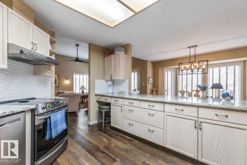 Kitchen featuring light wood-finish cabinetry, stainless steel appliances, granite countertops, and wood-finish flooring - 47 1130 Falconer Road, Edmonton, AB - Indoor Photo Showing Kitchen With Upgraded Kitchen
